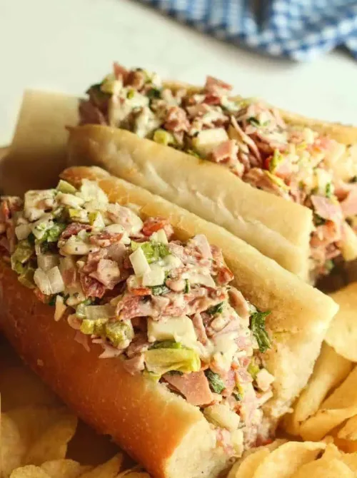 Chopped Italian subs filled with deli meats, peppers, and dressing on hoagie rolls—tailgate food on a budget that’s easy to prep and perfect for feeding a crowd.