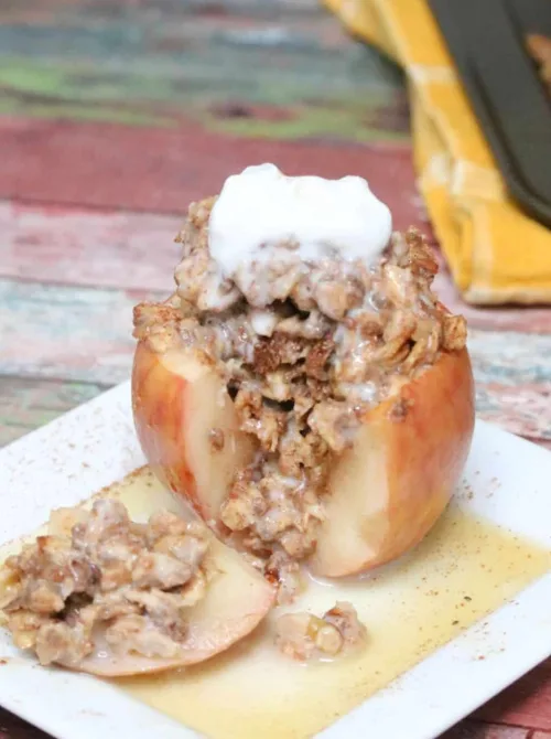 Baked apple stuffed with cinnamon oat crumble and topped with a dollop of cream, served on a white plate—an irresistible example of things to make with apples for easy fall recipes.