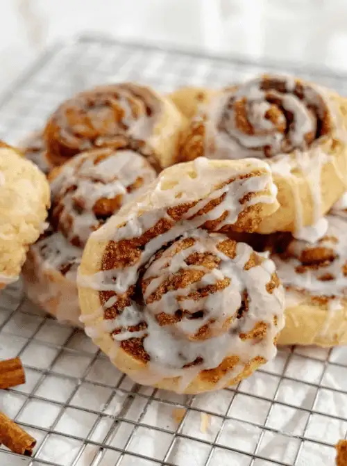 Homemade cinnamon rolls filled with apple pie filling and topped with vanilla glaze, a sweet and cozy treat for anyone wondering what to make with apples or searching for fall bread recipes.