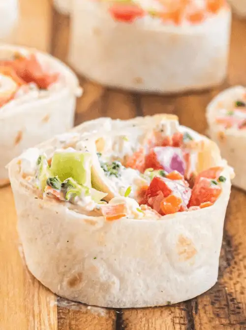 Colorful veggie pinwheel made with cream cheese and fresh chopped vegetables in a tortilla—easy tailgate food on a budget that’s perfect for a crowd.