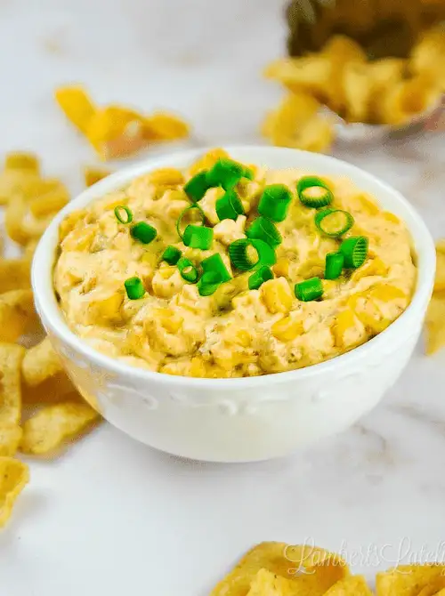 Creamy crack corn dip topped with fresh green onions, served in a white bowl with corn chips — a crowd-favorite among easy game day dips.