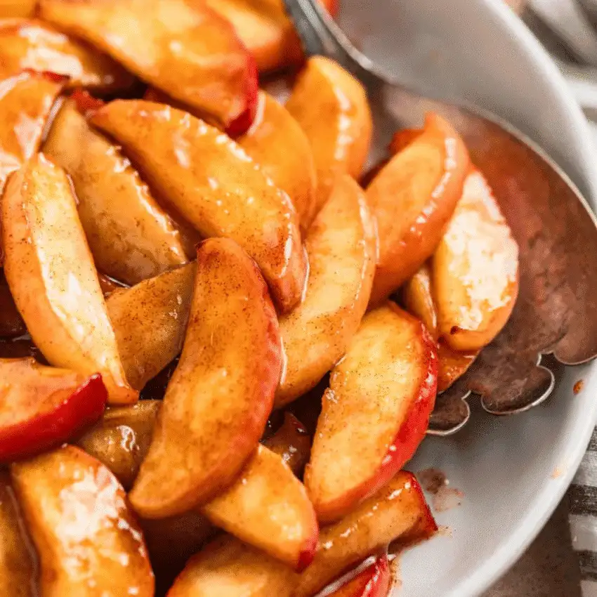 Close-up of cinnamon-glazed apple slices glistening in syrup, served in a white bowl—warm, buttery, and one of the most comforting things to make with apples for easy fall recipes and holiday sides.