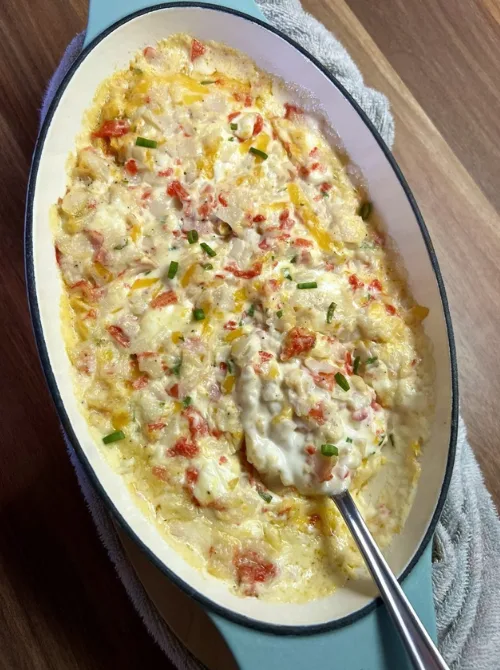 Creamy hot dip with melted cheese, red peppers, and fresh chives served in a teal baking dish — one of the ultimate easy game day dips for sharing.