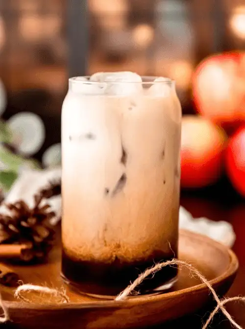 Layered iced apple crisp macchiato in a glass with dark espresso and creamy milk swirl—cozy, refreshing, and a visually stunning fall drink that’s perfect for easy fall recipes and seasonal things to make with apples.