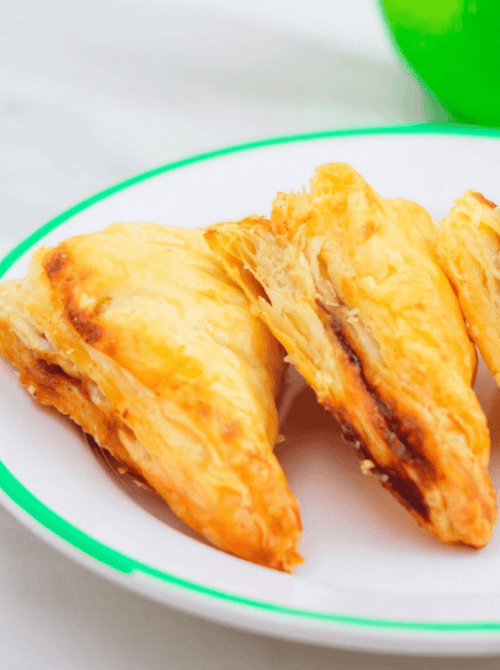 Golden brown apple turnovers with flaky puff pastry on a white plate – an easy and delicious fall treat made with apples.