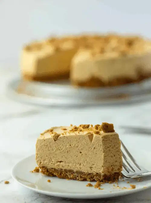 Slice of no-bake pumpkin cheesecake with a gingersnap crust, topped with crumbled cookies — a creamy and easy pumpkin cheesecake recipe that’s perfect for using up leftover pumpkin purée.