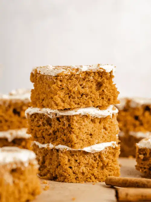 Stack of fluffy pumpkin bars topped with cream cheese frosting and a sprinkle of cinnamon—an easy fall dessert and delicious way to use up leftover pumpkin puree.