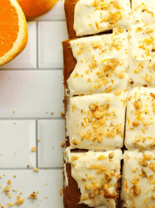 Close-up of frosted pumpkin cake squares topped with chopped nuts and orange zest, a delicious idea for what to make with leftover pumpkin puree—perfect for fall-inspired pumpkin cakes and cupcakes.