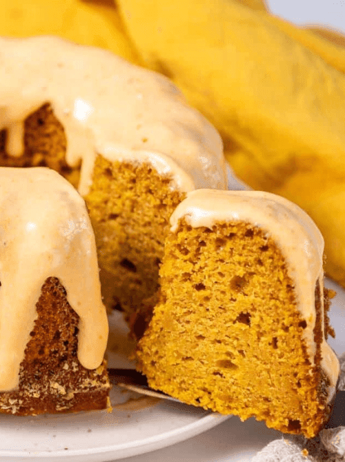 Moist pumpkin bundt cake with creamy glaze, sliced to show soft texture—an easy and delicious solution for what to make with leftover pumpkin puree in fall pumpkin cakes and cupcakes.