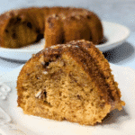 Moist slice of pumpkin bundt cake with chopped nuts on top, perfect for showcasing what to make with leftover pumpkin puree in rich, fall-inspired pumpkin cakes and cupcakes.
