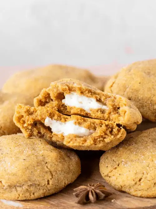 Soft pumpkin cookies with a creamy cheesecake filling, shown with one split open to reveal the center — a cozy fall treat that’s perfect for using up leftover pumpkin purée and a creative twist on easy pumpkin cheesecake.