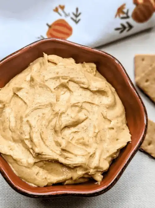 Creamy pumpkin cheesecake dip in a brown bowl, ready to be served with graham crackers — an easy, no-bake fall dessert that’s perfect for using up leftover pumpkin purée.