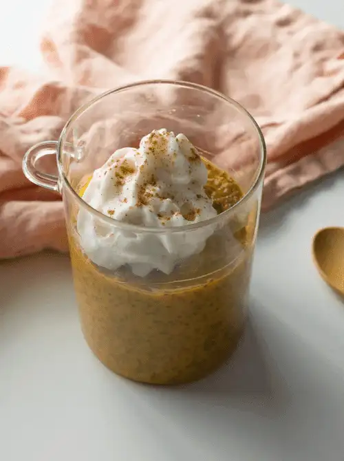 Glass mug of pumpkin chia pudding topped with whipped cream and cinnamon—an easy, healthy pumpkin dessert and creative way to use leftover pumpkin puree.