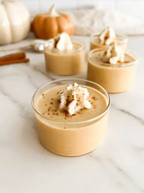 Glass cups filled with creamy pumpkin custard, topped with whipped cream and cinnamon—an easy and elegant pumpkin dessert perfect for using leftover pumpkin puree.S