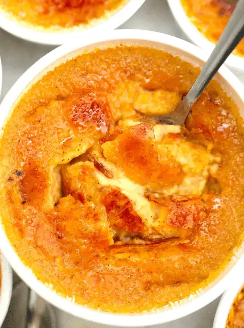 Close-up of pumpkin pie crème brûlée with a caramelized sugar crust cracked open to reveal creamy custard inside—an elegant pumpkin dessert idea for using leftover pumpkin puree.