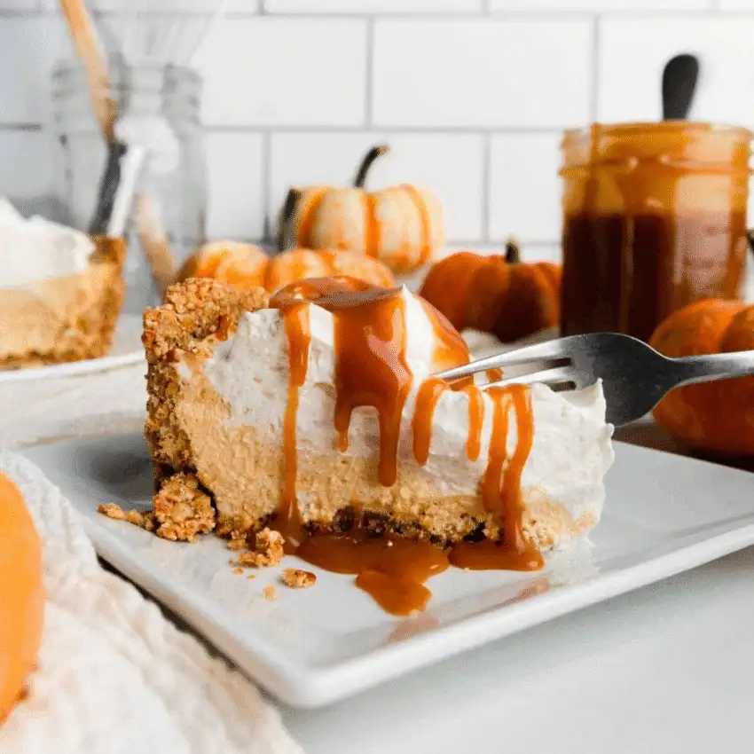 Slice of no-bake pumpkin pie topped with whipped cream and drizzled caramel sauce, served on a white plate—an indulgent way to use leftover pumpkin puree.