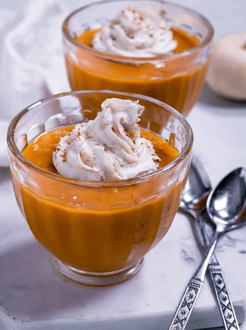 Glass bowls of silky pumpkin pie custard topped with whipped cream and sprinkled with spice—an elegant, dairy-free pumpkin dessert and delicious way to use leftover pumpkin puree.