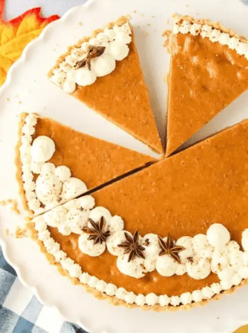 Pumpkin tart with a smooth spiced filling, decorated with piped whipped cream and star anise—an elegant fall dessert and beautiful way to use leftover pumpkin puree.