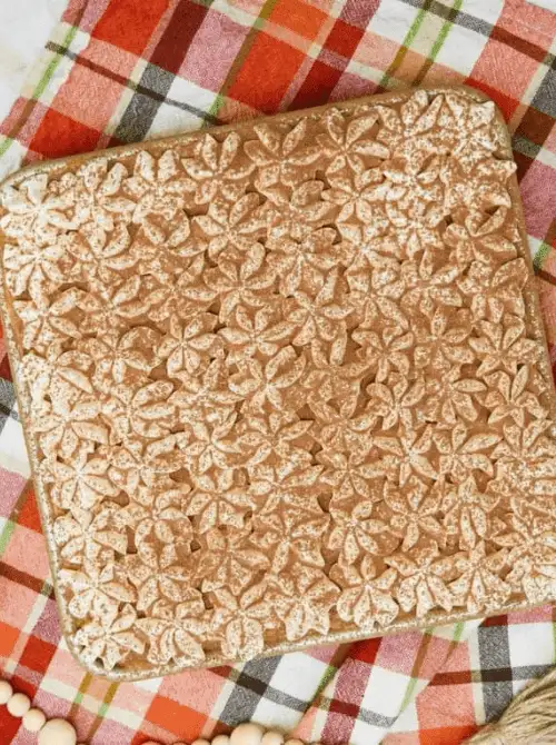 Decorative pumpkin crisp topped with leaf-shaped pie crust cutouts and powdered sugar—an eye-catching fall pumpkin dessert and creative way to use leftover pumpkin puree.