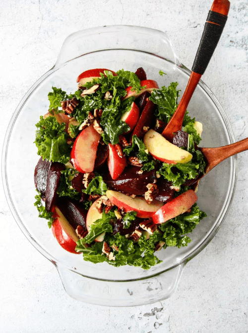 Kale and roasted beet salad with crisp apple slices and chopped pecans in a glass bowl—nutritious, colorful, and a fresh take on things to make with apples for easy fall recipes.