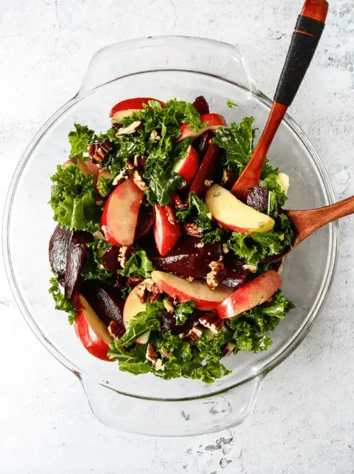 Kale and roasted beet salad with crisp apple slices and chopped pecans in a glass bowl—nutritious, colorful, and a fresh take on things to make with apples for easy fall recipes.