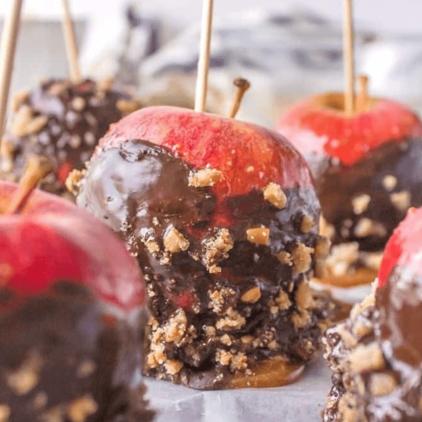 Chocolate-dipped caramel apples with chopped nuts on sticks – festive things to make with apples and fun, simple fall treats for parties and kids.
