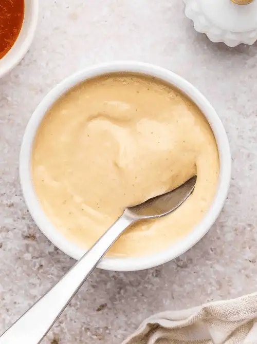 Creamy homemade dipping sauce in a white bowl with spoon, a simple and delicious choice for easy game day dips.