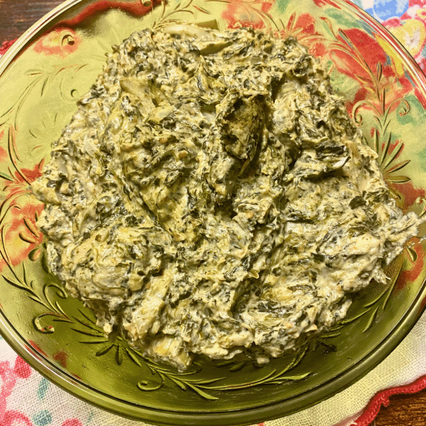 Bowl of creamy spinach dip served in a vintage glass dish, perfect for crackers or chips at a budget-friendly game day gathering.