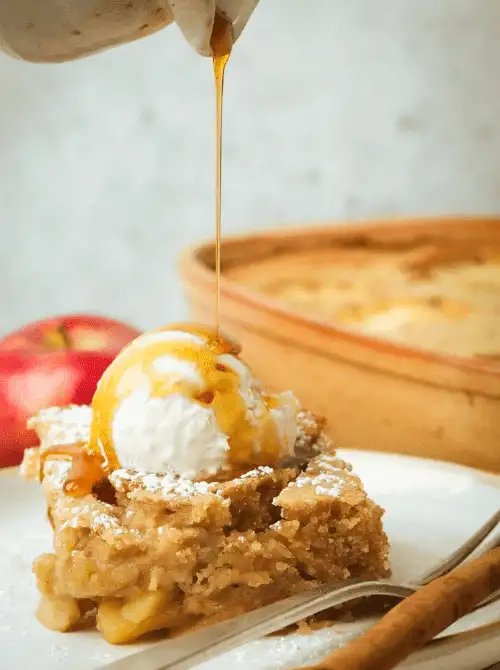 Warm apple blondie topped with vanilla ice cream and drizzled maple syrup—an easy fall dessert that captures the cozy, cinnamon-kissed flavors of baked apples and spice.
