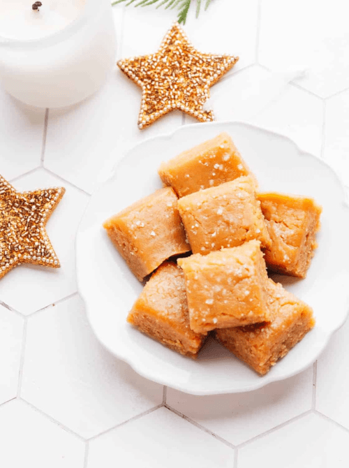 Squares of homemade peanut butter fudge on a white plate, a festive DIY Christmas gift and one of the easiest edible gifts to share during the holidays.