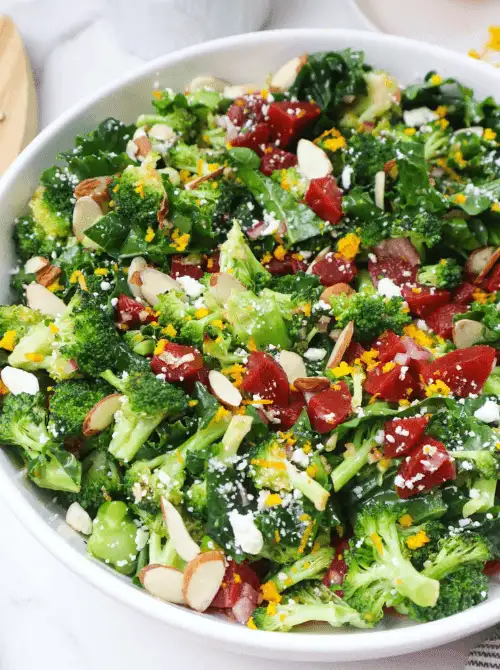 Fresh broccoli salad with kale, cranberries, almonds, and feta in a white bowl—an easy, colorful addition to Budget-Friendly Thanksgiving Vegetable Sides.