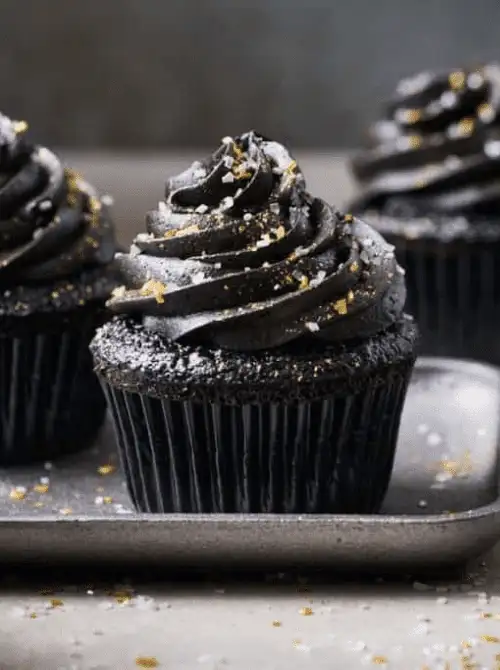 Elegant black cupcakes with dark chocolate frosting and gold sprinkles—make-ahead Halloween party food that’s spooky, stylish, and perfect for grown-up gatherings.