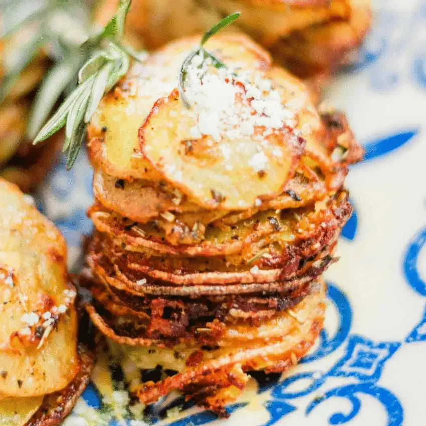 Stack of crispy muffin tin potatoes garnished with rosemary and parmesan, featured in Budget-Friendly Thanksgiving Sides and Easy Potato Recipes.