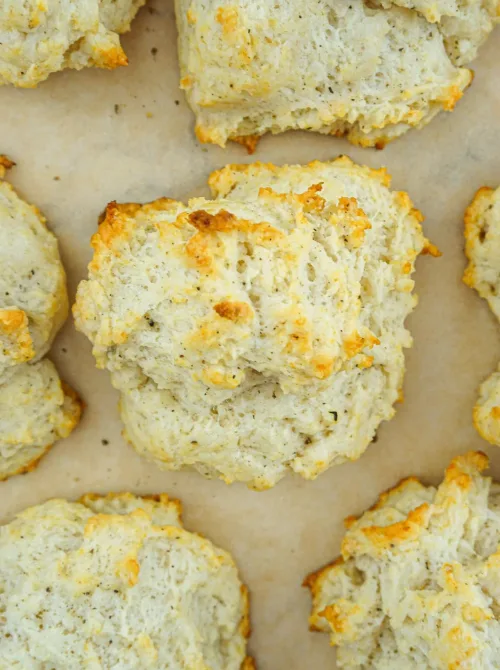 Golden brown homemade drop biscuits on parchment paper, a quick and budget-friendly Thanksgiving side dish.