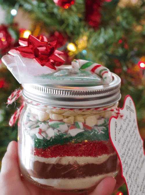 Layered candy cane hot chocolate mason jar recipe decorated with a bow and gift tag, a festive idea for DIY Christmas gifts.
