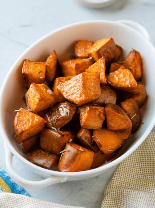 Golden roasted sweet potato cubes in a white serving dish, part of Budget-Friendly Thanksgiving Sides and Easy Potato Recipes for a simple, flavorful holiday option.