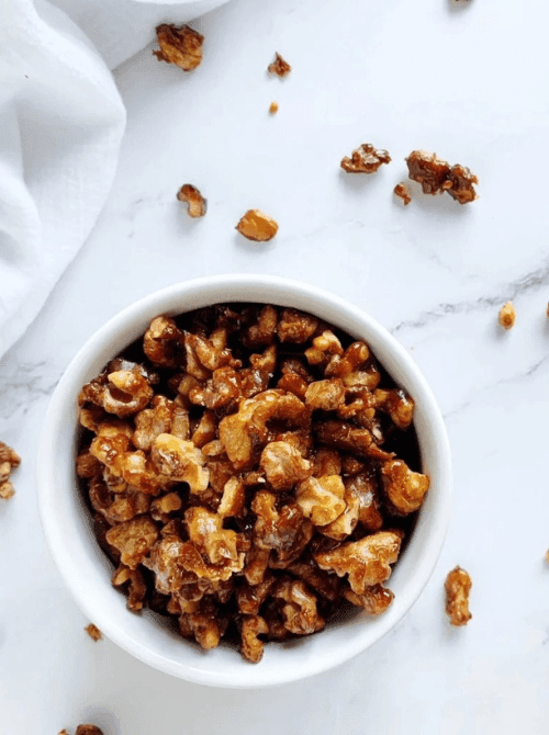 Bowl of homemade caramelized walnuts on a marble surface, a simple DIY Christmas gift and easy edible gift idea for the holidays.