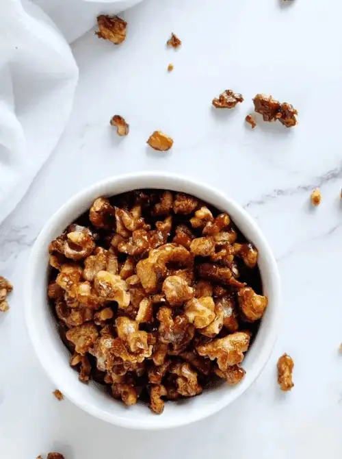 Bowl of homemade caramelized walnuts on a marble surface, a simple DIY Christmas gift and easy edible gift idea for the holidays.