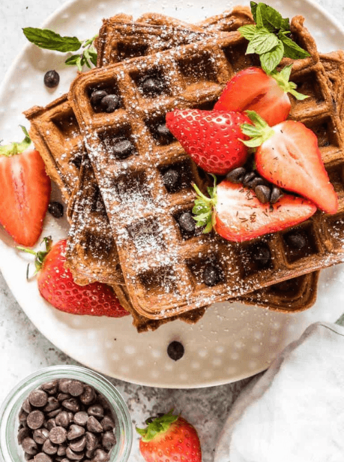 Chocolate chip waffles topped with fresh strawberries and powdered sugar – a fun idea for what to make with Thanksgiving leftovers and recipes that stretch your budget.