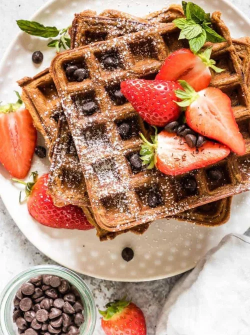 Chocolate chip waffles topped with fresh strawberries and powdered sugar – a fun idea for what to make with Thanksgiving leftovers and recipes that stretch your budget.