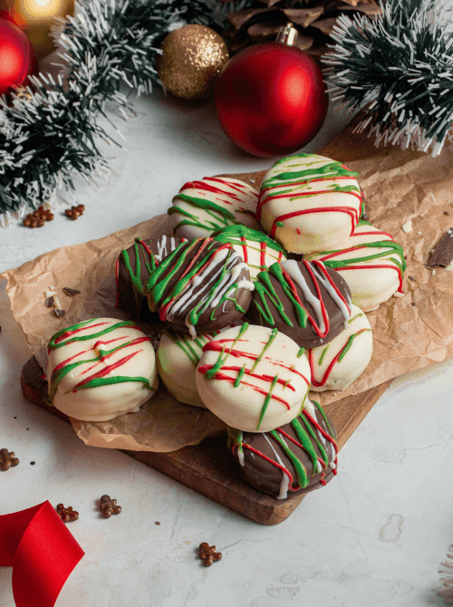 Christmas Oreos dipped in chocolate and drizzled with red and green icing, a festive DIY Christmas gift idea featuring cookies and bars.