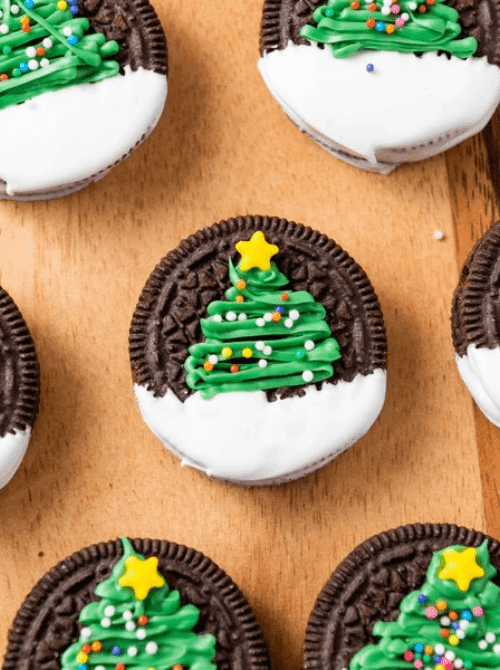 Christmas Oreos decorated with green icing Christmas trees and sprinkles, a fun DIY Christmas gift idea featuring cookies and bars.