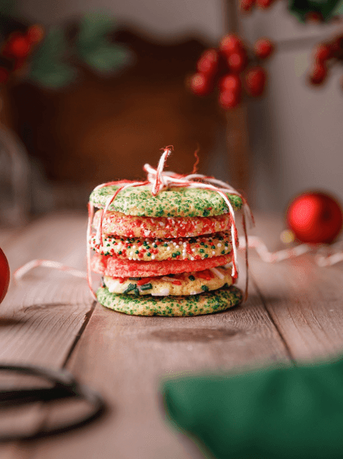 Stack of colorful Christmas cookies tied with string, a cheerful DIY Christmas gift idea featuring cookies and bars.