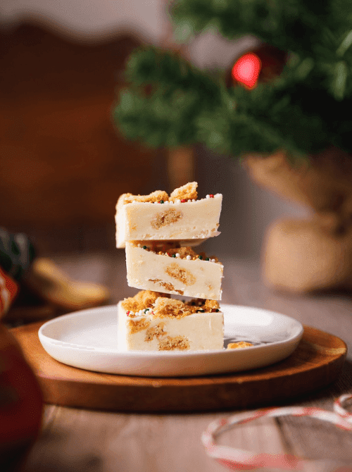 Stack of Christmas sugar cookie fudge squares on a plate, a sweet DIY Christmas gift idea featuring cookies and bars.