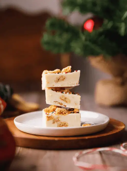 Stack of Christmas sugar cookie fudge squares on a plate, a sweet DIY Christmas gift idea featuring cookies and bars.