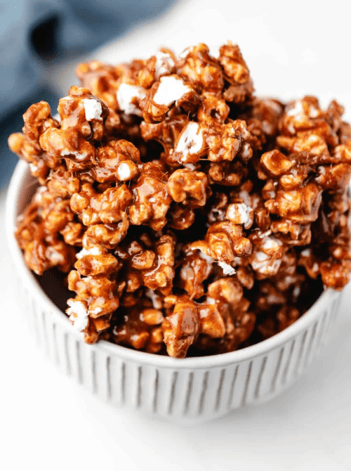 Homemade cinnamon bun caramel popcorn in a white bowl, a cozy DIY Christmas gift and easy edible gift idea for the holiday season.