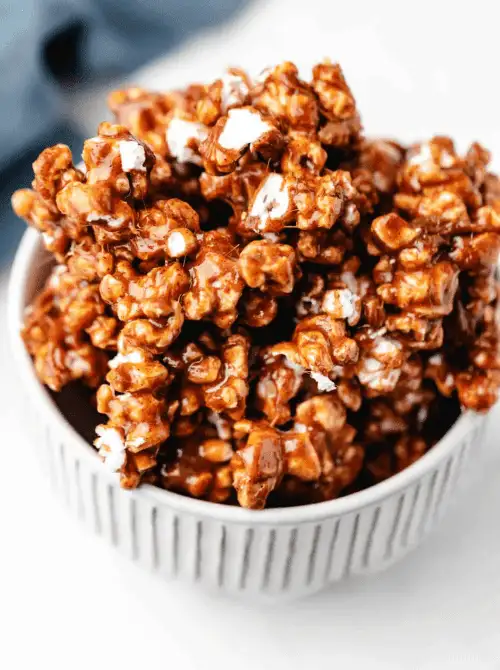 Homemade cinnamon bun caramel popcorn in a white bowl, a cozy DIY Christmas gift and easy edible gift idea for the holiday season.
