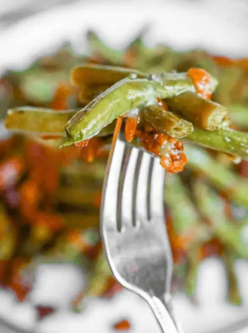 Close-up of forkful of tender green beans with crispy bacon and glaze—an easy, flavorful choice for Budget-Friendly Thanksgiving Vegetable Sides.