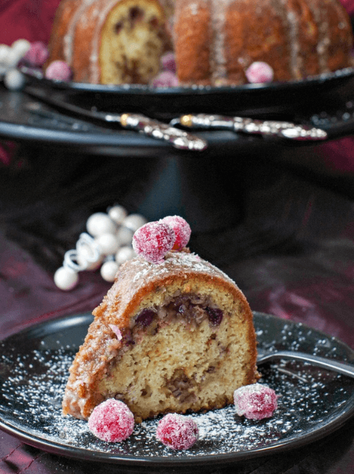 Slice of cranberry bundt cake with sugared cranberries on top – a delicious idea for what to make with Thanksgiving leftovers and recipes that stretch your budget.