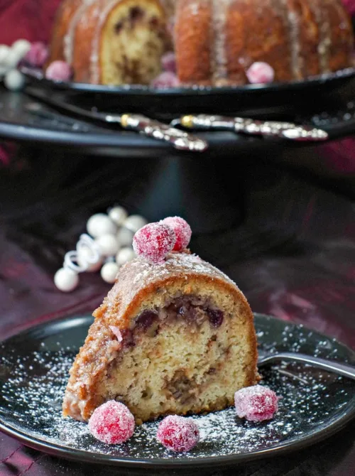 Slice of cranberry bundt cake with sugared cranberries on top – a delicious idea for what to make with Thanksgiving leftovers and recipes that stretch your budget.